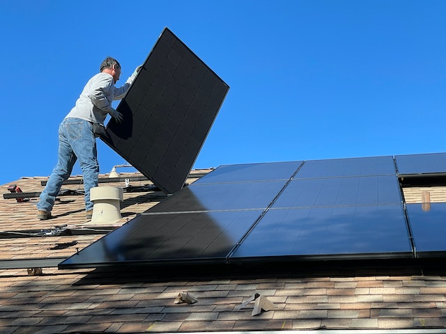 Man on rooftop installing solar panels